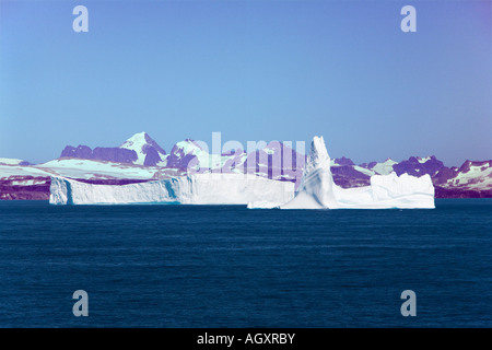 Gros icebergs flottent dans la mer au large de la côte sud-ouest du Groenland avec une montagne le long de la côte au-delà Banque D'Images