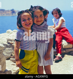 Deux jolies petites filles avec leurs bras autour de l'autre dans une étreinte sourire joyeusement à l'appareil photo de la Méditerranée Turquie Kusadasi Banque D'Images