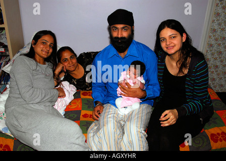 La famille sikh à la maison avec le père tenant un bébé de 19 jours et de 23 ans et mère à droite avec Soeur et grand-mère, au Royaume-Uni. Banque D'Images