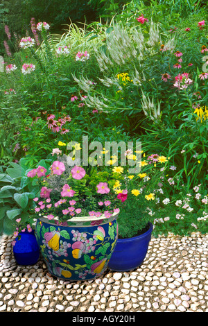 Terrasse Pavée blanc avec de grands pots en céramique orientale avec des couleurs correspondant au jardin de fleurs sauvages de rose blanc et jaune Banque D'Images