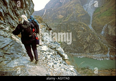 Chine Yunnan la Gorge du tigre bondissant deux touristes randonnée pédestre sentier étroit sur la falaise au-dessus de la rivière Jinsha Banque D'Images
