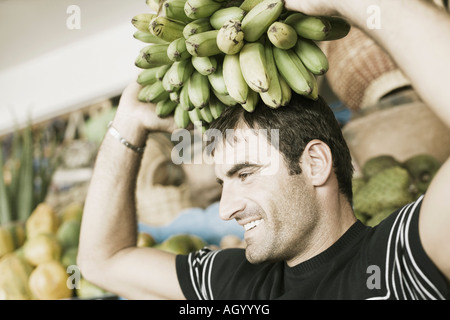 Close-up of a Mid adult man portant un régime de bananes sur la tête Banque D'Images