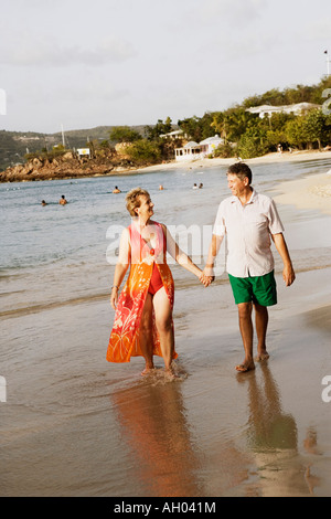 Mature Woman holding un haut la main de l'homme et la marche sur la plage Banque D'Images