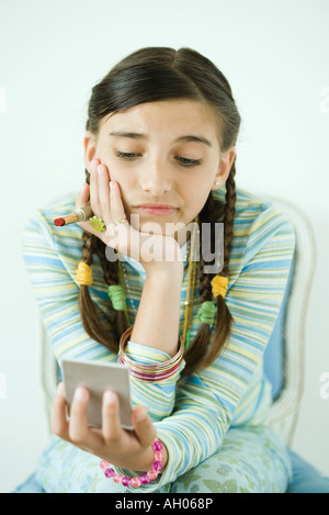 Girl looking at self in hand mirror, fronçant Banque D'Images