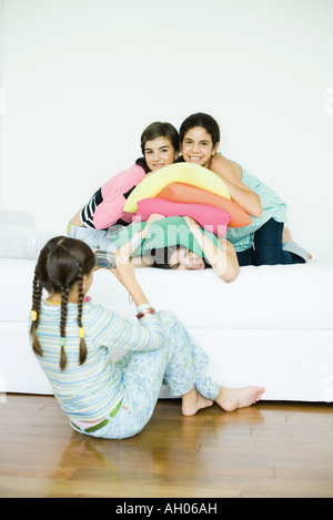 Trois jeunes amis féminins posing while quatrième ami prend photo Banque D'Images