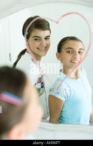 Deux jeunes femmes à la recherche d'amis à miroir, coeur dessiné sur le rouge à lèvres avec miroir Banque D'Images