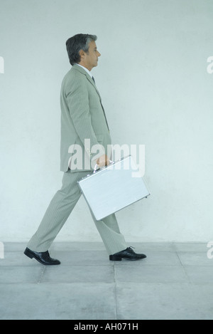 Businessman carrying briefcase, side view, portrait Banque D'Images