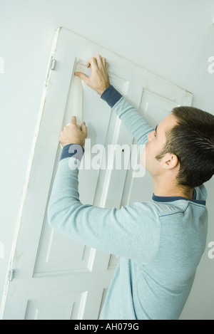 Man putting bande sur la menuiserie de porte de la préparation avant peinture Banque D'Images