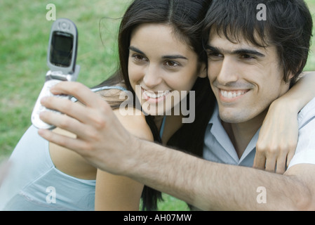 Jeune couple posing while man contient jusqu'téléphone cellulaire pour prendre une photo Banque D'Images