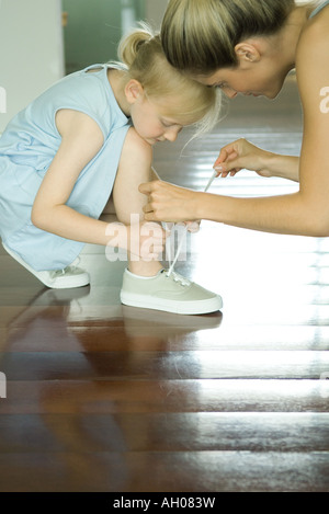 Aider la mère petite fille attacher lacets Banque D'Images