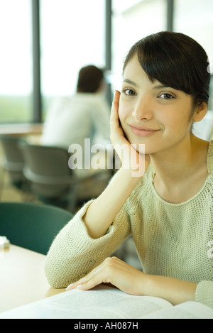 Young woman studying in university library, smiling at camera Banque D'Images