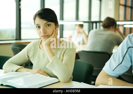 Young woman studying in university library, looking at camera Banque D'Images