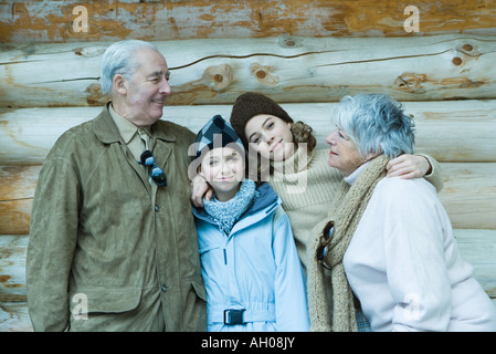 Et des ados filles préadolescentes avec les grands-parents, standing in front of log cabin avec les bras autour de l'autre, portrait Banque D'Images