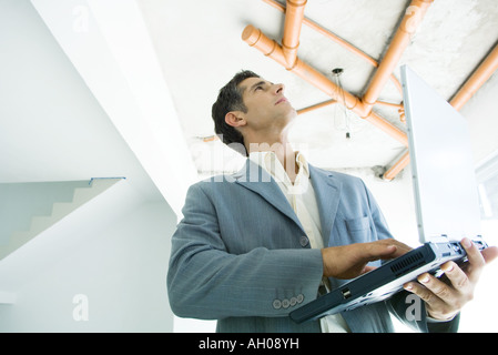 L'homme bien habillé à l'aide d'ordinateur portable, l'inspection de l'intérieur d'accueil non fini Banque D'Images