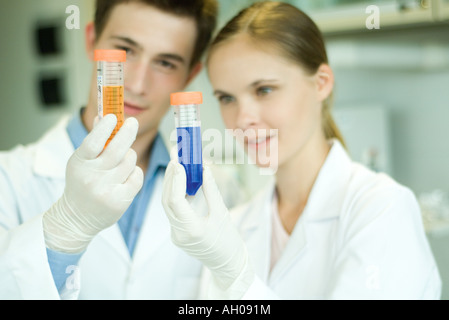 Les jeunes hommes et femmes scientifiques holding up test tubes Banque D'Images