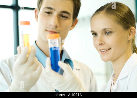 Les jeunes hommes et femmes scientifiques holding up test tubes Banque D'Images