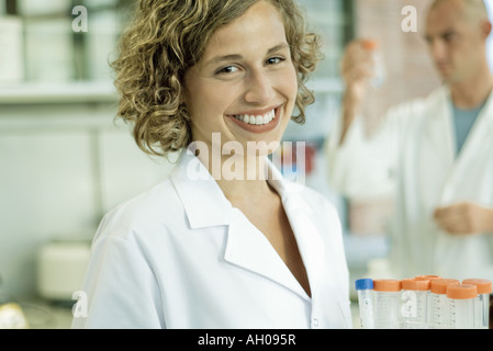 Femme lab worker holding rack vide de tubes à essai, smiling at camera, portrait Banque D'Images