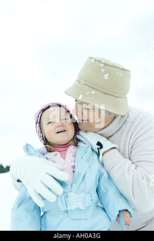 Grand-Mère embrassant tout-petit dans la neige, les deux smiling Banque D'Images