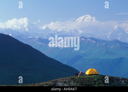 Un randonneur sur ridge se détend à côté de sa tente avec le Mont McKinley en Alaska l'arrière-plan Banque D'Images