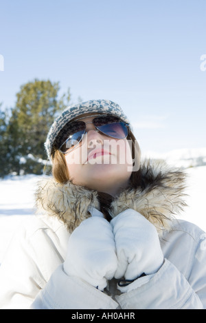 Teenage girl wearing parka et lunettes de soleil dans la neige, tête en arrière, portrait Banque D'Images