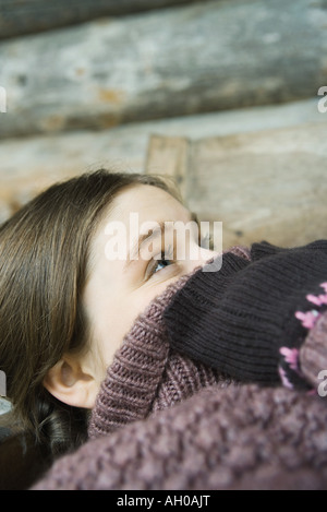 Teenage girl holding pointe de cou pull sur visage, looking up, Close-up Banque D'Images