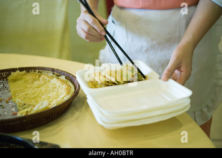 Le personnel de service des aliments à l'aide de baguettes de placer la nourriture dans en polystyrène Banque D'Images