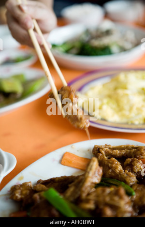 Plusieurs plats préparés sur la table, personne d'atteindre pour la viande avec des baguettes, cropped view Banque D'Images