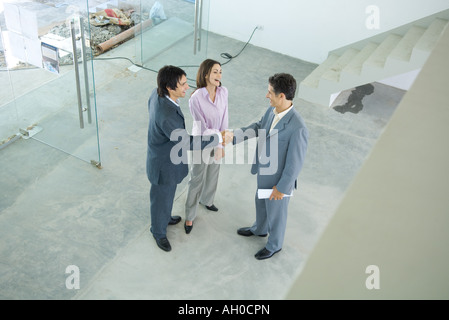 Homme vrai agent immobilier standing in home intérieur avec jeune couple, pleine longueur, high angle view Banque D'Images