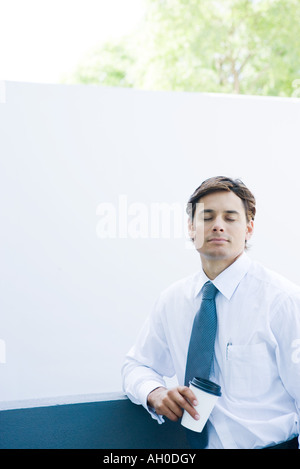 Businessman holding Coffee Cup, les yeux fermés Banque D'Images