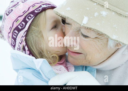 Girl kissing grand-mère sur la joue, à la fois habillé en vêtements d'hiver, close-up Banque D'Images