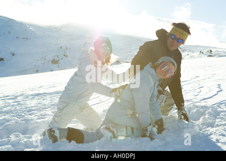 Son père et ses deux filles crouching in snow, smiling Banque D'Images