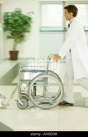 Médecin Homme poussant un fauteuil roulant vide, blurred motion Banque D'Images