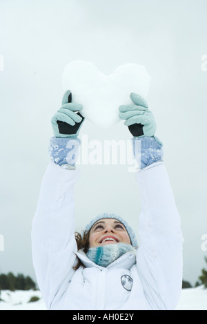 Young woman holding up coeur fait de neige Banque D'Images