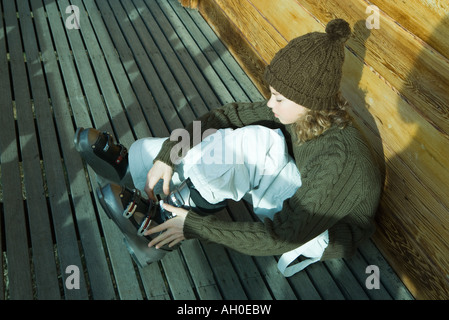 Teenage girl sitting on ground, mise sur les chaussures de ski Banque D'Images