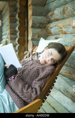 Teenage girl reading book, smiling at camera, vêtu de vêtements d'hiver Banque D'Images