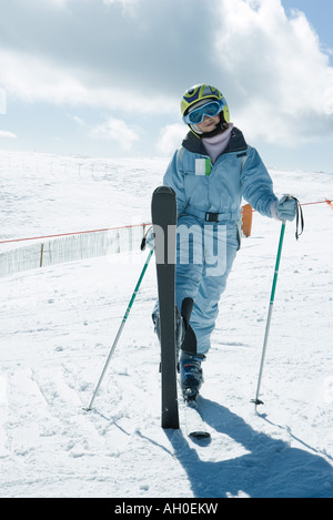 Jeune skieur debout avec une jambe, smiling at camera, portrait Banque D'Images