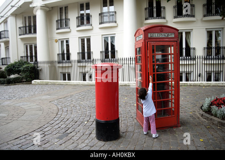 Enfant par de vieux fort et téléphone rouge red letter box, St Katharine Docks, London, England, UK Banque D'Images