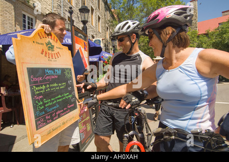 Canada Québec Vieux-québec Rue Petit Champlain Biking couple checking out restaurant menu avec l'hôte Banque D'Images