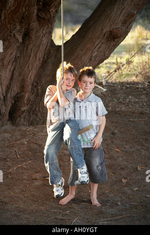 7 garçons s'amusant sur rope swing Banque D'Images