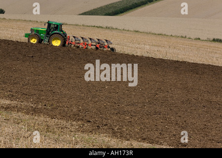 Mouettes suivent un tracteur vert et jaune comme il laboure un champ de chaume dans le Lincolnshire Wolds, Angleterre Banque D'Images