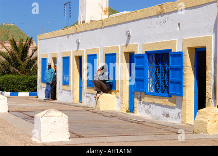 Maroc , Marrakech , scène africaine traditionnelle de pêcheurs vous détendre sur quai par les bureaux de douane au soleil avec ciel bleu et le palm Banque D'Images