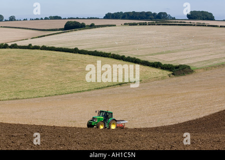 Mouettes suivent un tracteur vert et jaune comme il laboure un champ de chaume dans le Lincolnshire Wolds, Angleterre Banque D'Images