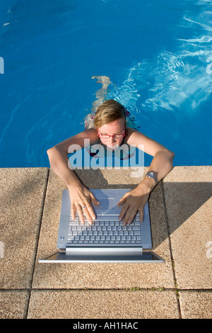 Bourreau de dame de la saisie sur ordinateur portable durant vos vacances dans la piscine Banque D'Images