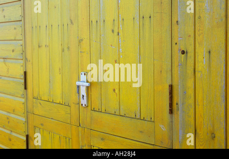Close up detail de porte en bois teinté jaune vif sur une cabane ou un local ou de kiosque ou de la cabine avec la poignée de porte en aluminium Banque D'Images