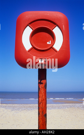 Close up de l'équipement de sauvetage rouge sur rouge post avec plage de sable blanc et bleu et gris ondulation calme mer et ciel bleu clair Banque D'Images