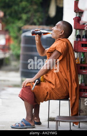 Le moine bouddhiste de boire une bouteille de coca cola. Katmandou, Népal Banque D'Images