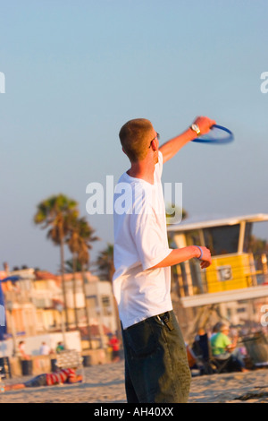 Un jeune homme de race blanche attrape un frisbee dans la fin d'après-midi sur une plage de Californie. Banque D'Images