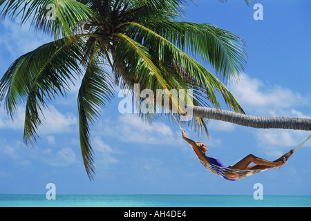 Woman relaxing in hammock sous palm tree Banque D'Images