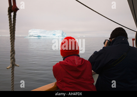 Couple on cruise ship prendre photo de gros iceberg passant par sur une mer calme dans la baie de Disko, sur la côte ouest du Groenland Banque D'Images