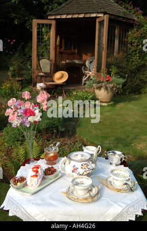 Service à thé de l'après-midi sur la pelouse à l'extérieur de maison d'été dans un jardin anglais Banque D'Images